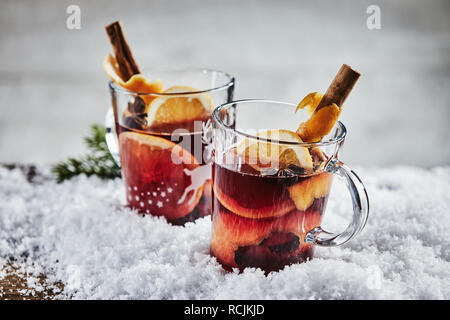 Chaud chaud épicé traditionnel Gluhwein ou vin rouge pour Noël avec l'orange, la cannelle et la badiane servi dans deux tasses en verre en hiver neige Banque D'Images