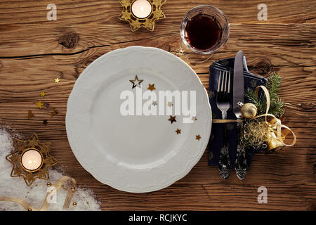 Noël Décoration de table avec des bougies allumées, un plateau vide décoré avec des étoiles, du vin rouge et des ustensiles et du ruban attaché avec serviette Banque D'Images