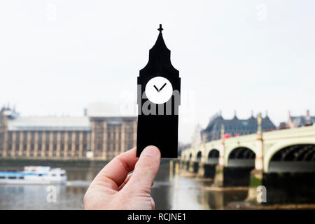 Libre de la main tenant une découpe de papier en forme de la tour de l'horloge du Palais de Westminster à Londres, Royaume-Uni Banque D'Images