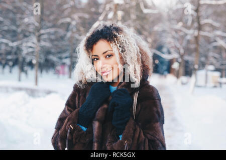 Piscine close up portrait of young belle mode femme avec les cheveux afro , porte manteau de fourrure dans winter park. La mode d'hiver, vacances de Noël concept. Banque D'Images