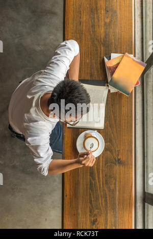 Asian man profiter nouvelle journée avec des livres et du café chaud Banque D'Images