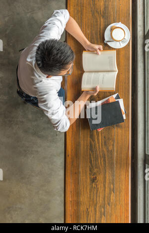 Jeune homme jouit de sa journée avec livres, sex cappuccino Banque D'Images