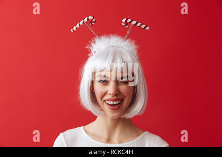 Image d'une jeune femme portant le costume carnaval noël sur mur rouge avec un clin. Banque D'Images