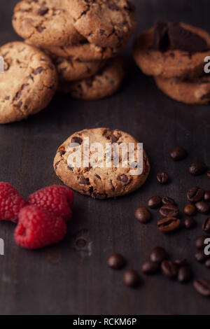 Cookies chocolat avec framboises rouges et les grains de café sur la table en bois sombre ancien. Frais hors du four. Banque D'Images