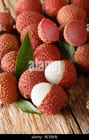 Litchis frais et délicieux avec des feuilles vertes sur une table en bois vertical. Banque D'Images