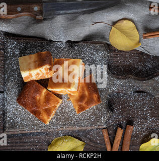 Square des tranches de fromage cottage et de la citrouille sur une planche en bois, le dessert est saupoudrée de sucre glace, vue du dessus Banque D'Images