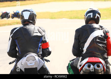 Deux hommes en costumes cuisson sur leurs motos attendent de commencer sur le circuit Banque D'Images