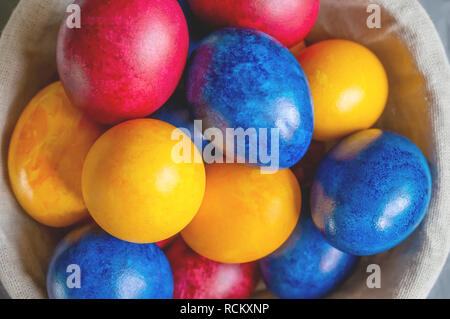 Les oeufs de Pâques colorés couché dans un panier sur un magnifique arrière-plan. Vue de dessus. Brunch de Pâques. Banque D'Images