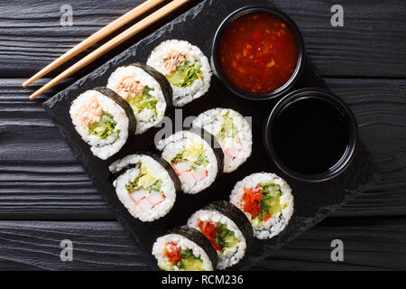 Rouleaux Futomaki avec divers matériaux ont servi avec des sauces close-up sur une liste de sélection sur la table supérieure horizontale. Vue de dessus Banque D'Images