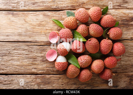 Fruits litchi mûr avec des feuilles vertes sur fond de bois horizontal. haut Vue de dessus Banque D'Images