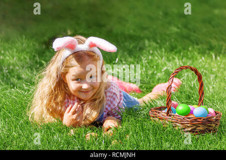 A cute little baby girl collecte des oeufs de Pâques dans le jardin. Banque D'Images