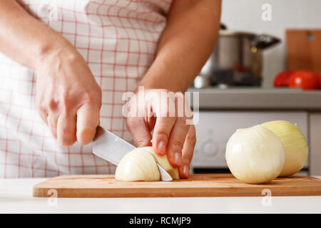 Femme cuisiner à la maison dans la cuisine, la coupe des oignons sur une planche de bois. Les aliments frais et sain. Close-up Banque D'Images