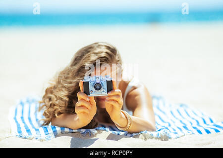 Gros plan sur l'appareil photo retro woman holding par une serviette à rayures sur le bord de la mer. Locations de capture de photos incroyables préserver ces memorie Banque D'Images