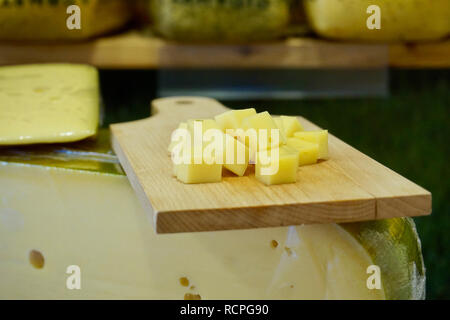 Découper le fromage hollandais avec des cubes de fromage sur le dessus d'un bloc de roue de fromage, à l'affiche dans les Pays-Bas (Hollande). Montre de fromage troué. Banque D'Images