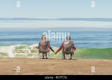 Couple assis dans des chaises pliantes sur l'océan Pacifique Beach en profitant de la vue Banque D'Images