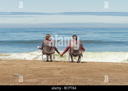 Couple assis dans des chaises pliantes sur l'océan Pacifique Beach en profitant de la vue Banque D'Images