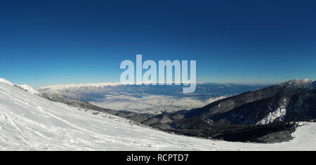 Vue panoramique du sommet du massif du Pirin pour la ville de Bansko en Bulgarie. Froide journée d'hiver, les sommets enneigés et ciel bleu clair. Banque D'Images