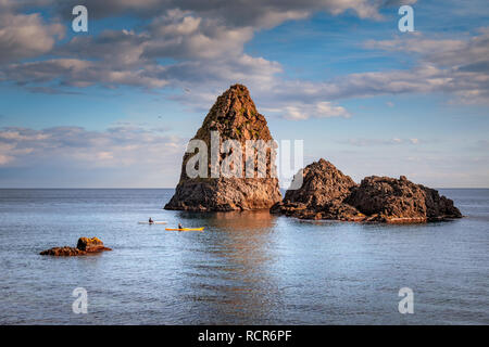 Deux gars canoë fermer la mer des piles de Aci Trezza durant une journée d'hiver ensoleillée, Sicile, Italie Banque D'Images