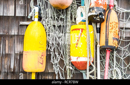 Les bouées du homard de couleur avec des filets de pêche accroché sur un mur extérieur Bardeaux dans Massachusetts Banque D'Images