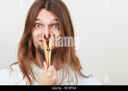 Homme avec clip clothespin peg sur son nez. Jeune brun sentiment désagréable odeur. Mauvaise odeur concept. Banque D'Images