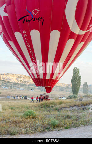 Hot Air Balloon ressemblant au drapeau turc atterrissant dans la Cappadoce, Turquie Banque D'Images