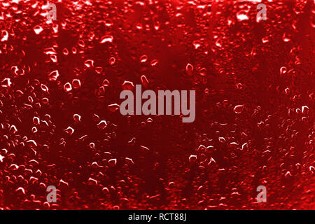 Un contraste élevé photo de gouttes de pluie sur une fenêtre avec verre couleur écarlate rouge vif Banque D'Images