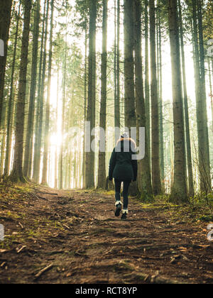 Morning Glory : jeune femme marchant sur un chemin de randonnée paisible dans les bois Banque D'Images