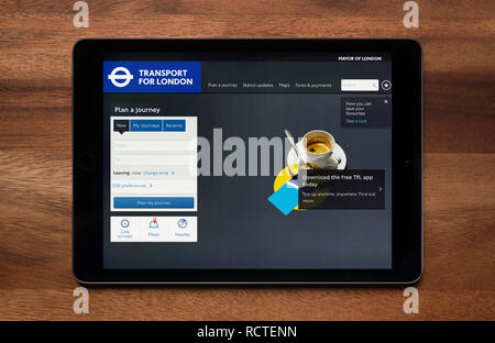 Le site internet de Transport for London (TfL) est vu sur un iPad tablet, qui repose sur une table en bois (usage éditorial uniquement). Banque D'Images