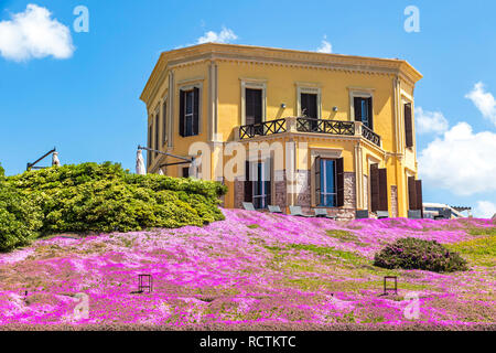 Alghero, Sardaigne, Italie - 25 Avril 2016 : vue pittoresque de construction de l'Hôtel Villa Mosca Alghero en vieille ville. Colline couverte de Saponaria flowerin Banque D'Images