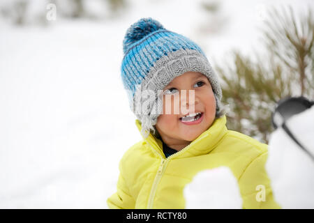 Rire bébé garçon portant des vêtements d'hiver dans une montagne couverte de neige. Banque D'Images