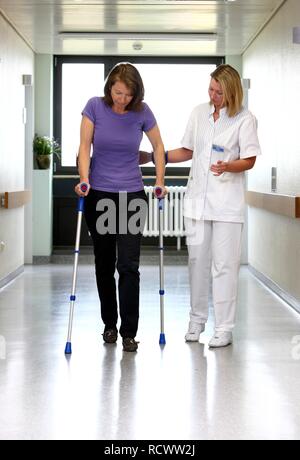 Aider un patient Infirmière essayant de marcher avec des aides à la marche, la mobilisation après une opération dans un hôpital Banque D'Images