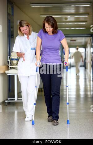 Aider un patient Infirmière essayant de marcher avec des aides à la marche, la mobilisation après une opération dans un hôpital Banque D'Images