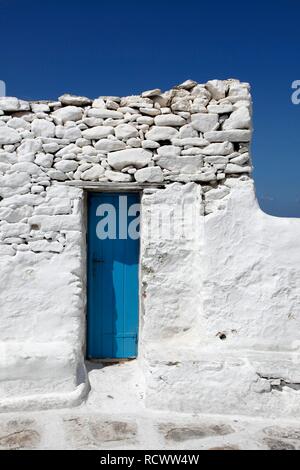 Petite porte en bois bleu étroit blanchis dans un mur de pierres brutes, Mykonos, Grèce, Europe Banque D'Images