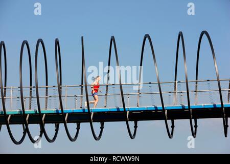 Jogger, runner, femme d'exécution sur un pont piétonnier, Slinky Ressorts pour la gloire, la forme de spirale pont sur le Canal de Rhine-Herne Banque D'Images