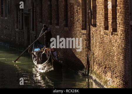 Venise, Italie - 21 mars 2018 : gondolier vénitien équitation les touristes sur gondola à travers le côté étroit canal à Venise. Banque D'Images