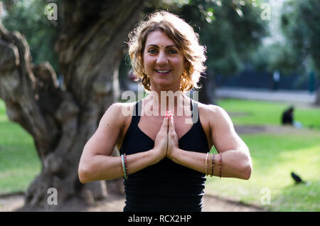 Belle jeune femme médite en yoga asana Padmasana - Lotus poser sur la terrasse en bois dans le parc de l'automne. Banque D'Images