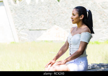 Vue de face d'un seul adolescent assis et de penser à côté de l'extérieur dans un parc Banque D'Images