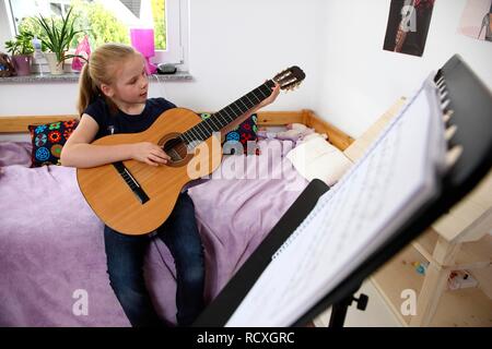 Fille, 10 ans, la pratique de la guitare dans sa chambre Banque D'Images