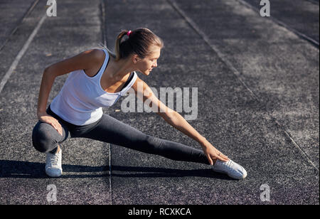 Young runner fit woman streching exercices avant l'extérieur. Athletic femme strech après entraînement à l'extérieur. Le sport et les gens concept. Banque D'Images