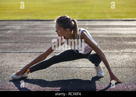 Young runner fit woman streching exercices avant l'extérieur. Athletic femme strech après entraînement à l'extérieur. Le sport et les gens concept. Banque D'Images