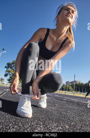 Le laçage des chaussures sport femme pour la préparation pour la formation au lever du soleil Banque D'Images