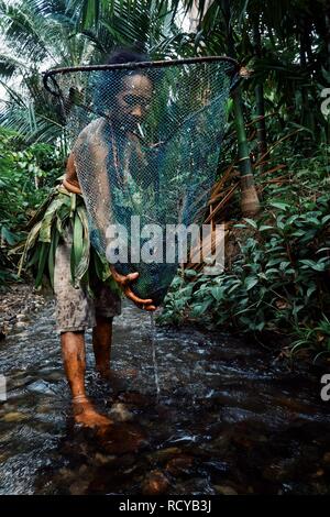 Muara Siberut, îles Mentawai / Indonésie - Aug 15 2017 : membre d'une tribu dame la pêche de petits alevins et crevettes dans la jungle stream Banque D'Images