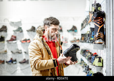 En choisissant l'homme veste hiver chaussures de trail pour la randonnée dans le magasin de sport Banque D'Images