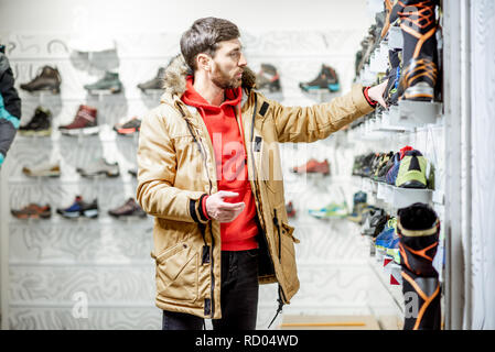 En choisissant l'homme veste hiver chaussures de trail pour la randonnée dans le magasin de sport Banque D'Images