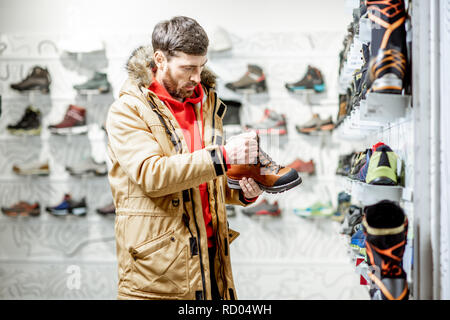 En choisissant l'homme veste hiver chaussures de trail pour la randonnée dans le magasin de sport Banque D'Images