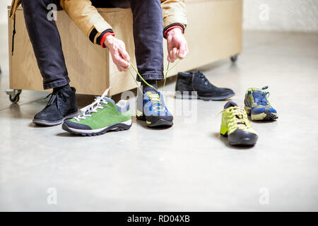 L'homme à essayer différentes chaussures de trail pour la randonnée dans le magasin de sport, close-up view avec pas de visage Banque D'Images