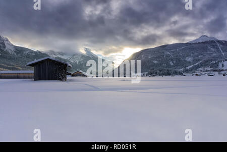 Paysage de montagne d'hiver au crépuscule. Le soleil qui illumine les nuages sombres. Le brouillard est de tomber dans la vallée. Banque D'Images