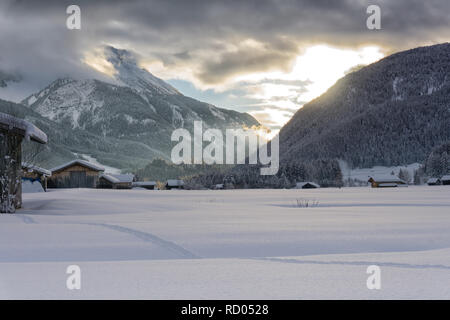 Paysage de montagne d'hiver au crépuscule. Le soleil qui illumine les nuages sombres. Le brouillard est de tomber dans la vallée. Banque D'Images