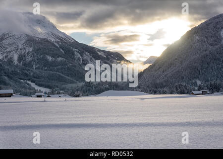 Paysage de montagne d'hiver au crépuscule. Le soleil qui illumine les nuages sombres. Le brouillard est de tomber dans la vallée. Banque D'Images