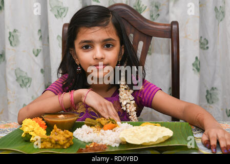 Indian girl enfant manger Onam Sadhya grand fête servi sur des feuilles de banane avec la main sur l'ONAM, Vishu Harvest Festival du Kerala, en Inde. Banque D'Images